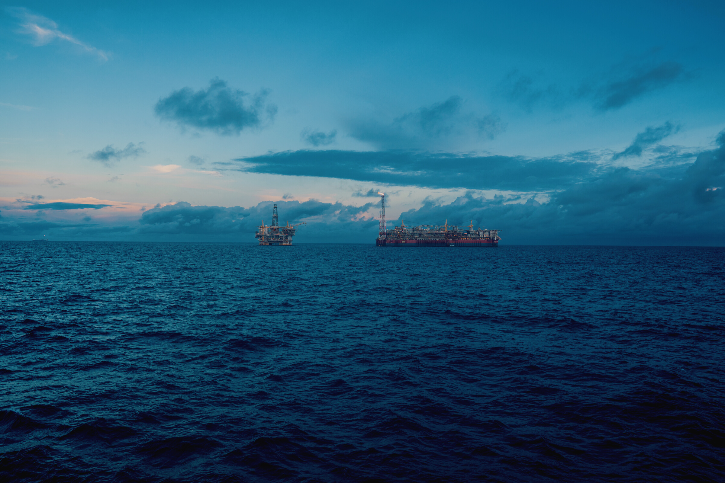 FPSO tanker vessel near Oil Rig platform. Offshore oil and gas industry. Flare is burning with smoke. View from supply vessel